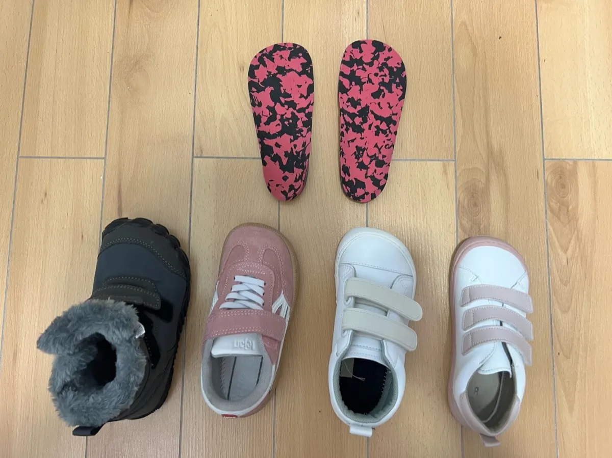 Soportes plantares personalizados junto a cuatro pares de zapatos infantiles revisados en Centro Podológico Henao para tratamiento ortopodológico